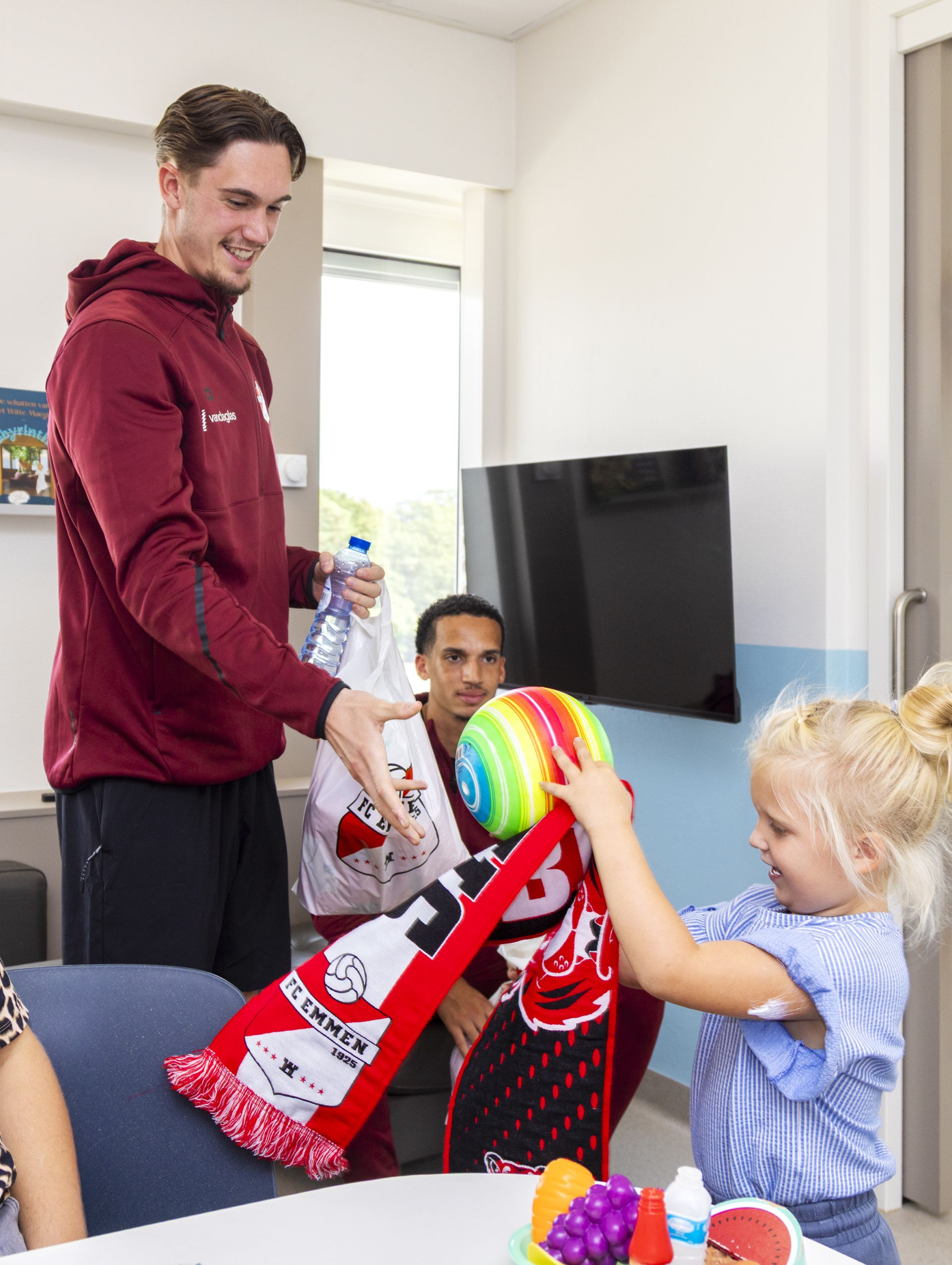 Patiëntje op de kinderafdeling krijgt een sjaal van een FC Emmen speler